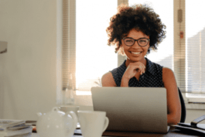 Foto de uma mulher Mulher sorrindo em frente ao seu notebook.