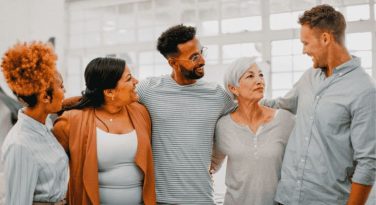 Foto com pessoas de diferentes raças e etnias abraçados e sorrindo um para os outros